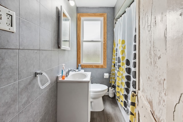 bathroom featuring curtained shower, hardwood / wood-style floors, toilet, vanity, and tile walls