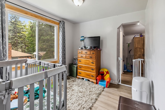 bedroom featuring light hardwood / wood-style flooring and a nursery area