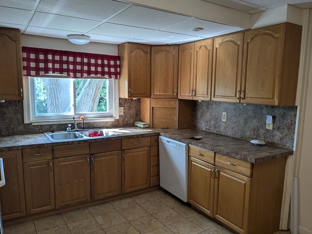 kitchen featuring a drop ceiling, white dishwasher, sink, light tile patterned floors, and tasteful backsplash