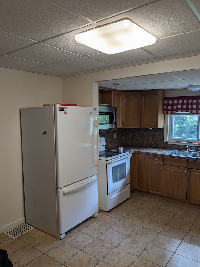 kitchen featuring light tile patterned flooring, white appliances, tasteful backsplash, and sink