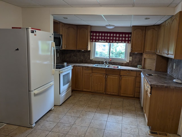 kitchen with sink, white appliances, a paneled ceiling, decorative backsplash, and light tile patterned flooring