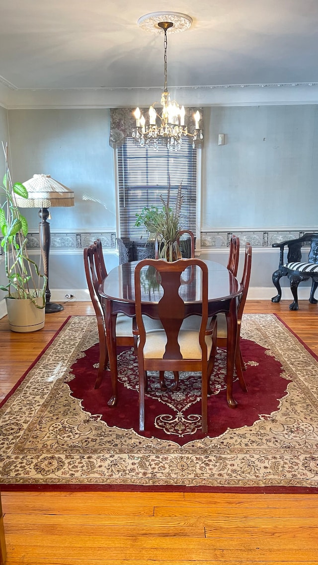 dining space featuring a notable chandelier, wood-type flooring, and ornamental molding