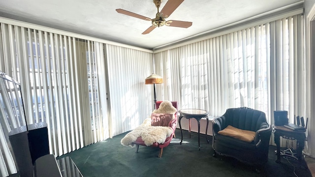 sitting room featuring dark colored carpet, plenty of natural light, ornamental molding, and ceiling fan