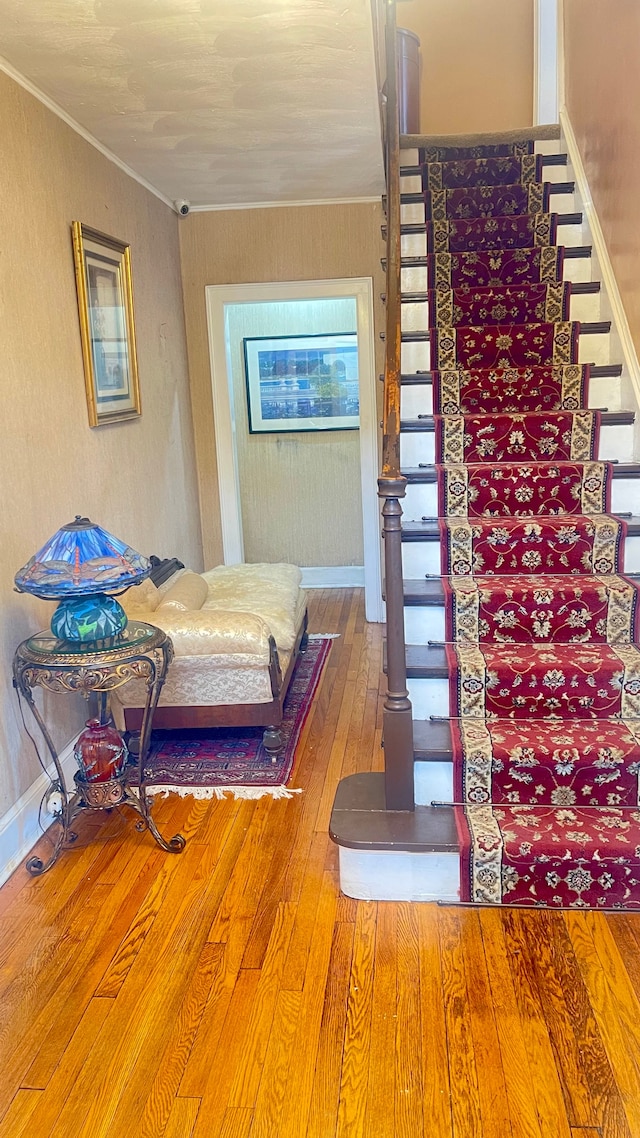 stairway featuring wood-type flooring and crown molding