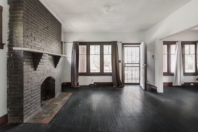 unfurnished living room featuring a fireplace, a textured ceiling, and dark hardwood / wood-style floors