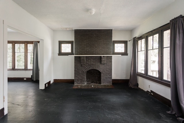 unfurnished living room with a fireplace, a textured ceiling, and plenty of natural light