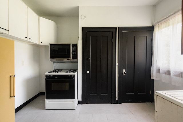 kitchen featuring white cabinets, light tile patterned flooring, and white gas range oven