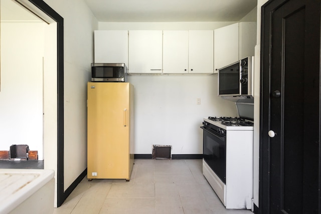 kitchen with white gas stove, white cabinets, and fridge