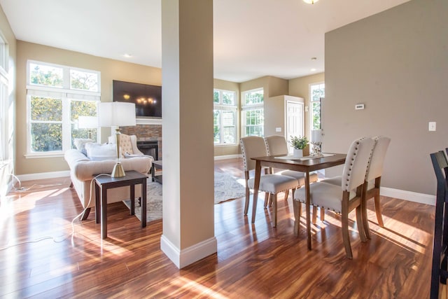 dining room with a stone fireplace and wood-type flooring