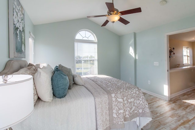 bedroom featuring light hardwood / wood-style flooring, multiple windows, lofted ceiling, and ceiling fan