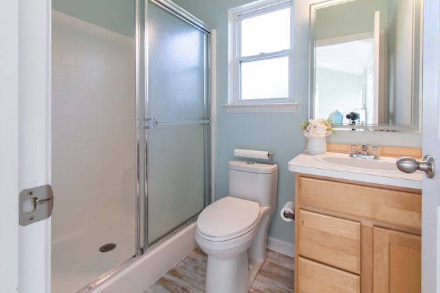 bathroom with hardwood / wood-style floors, vanity, toilet, and a shower with door