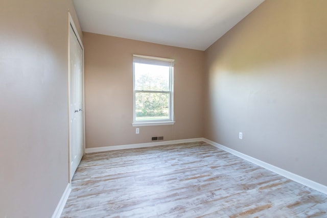 spare room with vaulted ceiling and light wood-type flooring