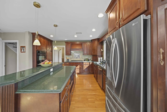 kitchen featuring a center island, hanging light fixtures, decorative backsplash, light wood-type flooring, and stainless steel appliances