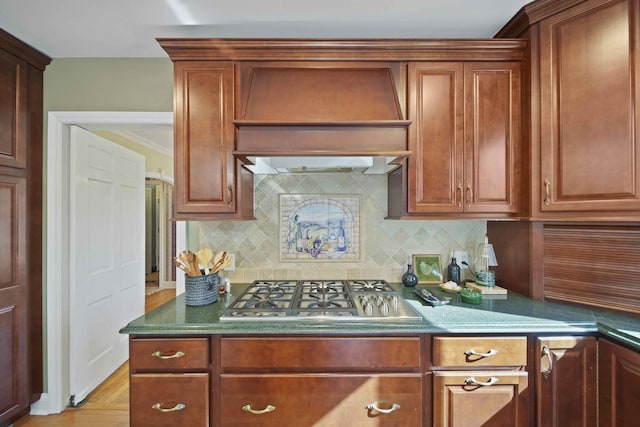 kitchen featuring tasteful backsplash, custom exhaust hood, light wood-type flooring, and stainless steel gas stovetop