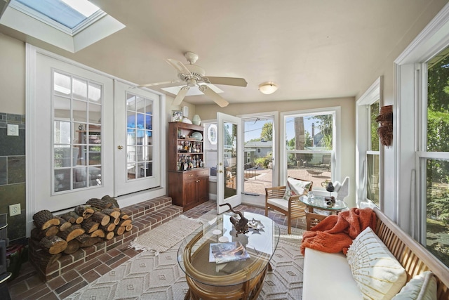 sunroom featuring vaulted ceiling with skylight, ceiling fan, and french doors