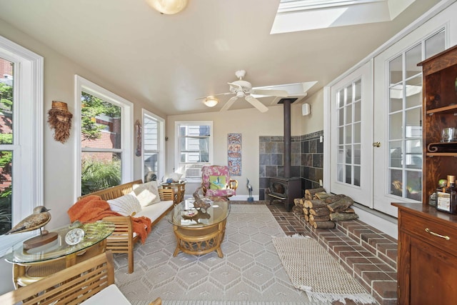 sunroom / solarium with a wood stove, ceiling fan, and vaulted ceiling with skylight