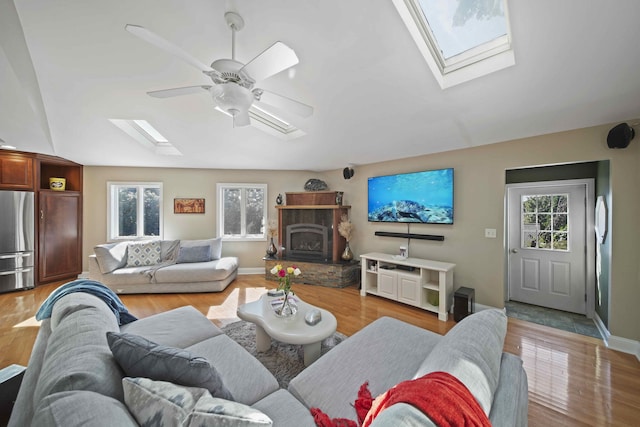 living room with a skylight, ceiling fan, and light wood-type flooring