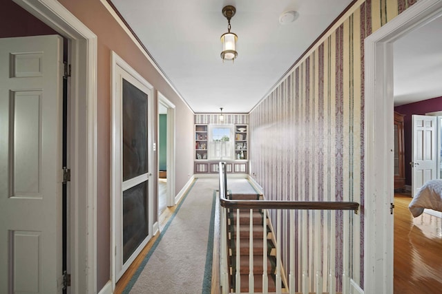 corridor with ornamental molding and hardwood / wood-style flooring