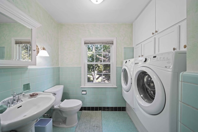 laundry room featuring tile walls, sink, and washing machine and clothes dryer