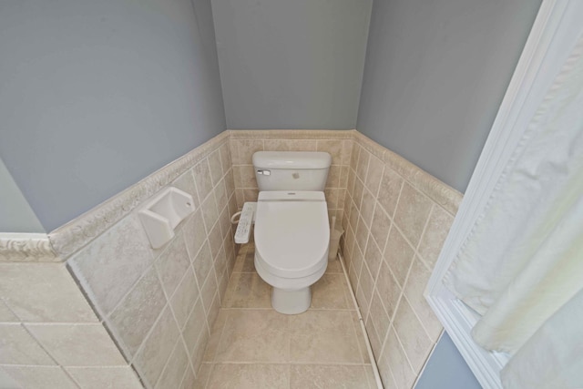 bathroom with tile patterned flooring, toilet, and tile walls