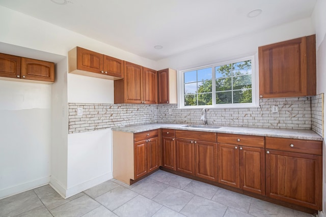 kitchen with light tile patterned floors, tasteful backsplash, light stone counters, and sink