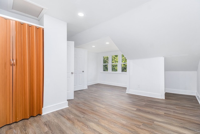 bonus room with hardwood / wood-style floors and vaulted ceiling