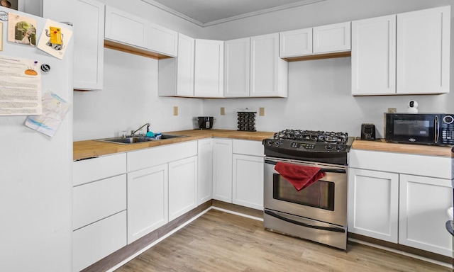 kitchen with white fridge, butcher block counters, white cabinetry, and stainless steel range with gas stovetop