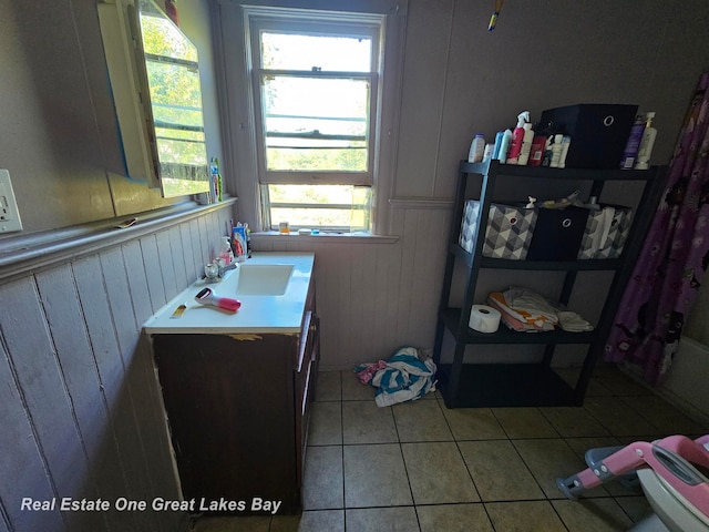 bathroom featuring tile patterned floors, wood walls, and vanity