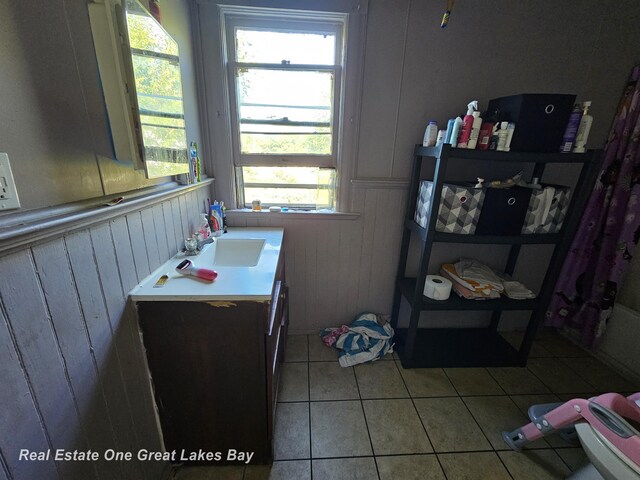 1209 S Fayette St, Saginaw, MI 48602 - bathroom featuring tile patterned flooring, vanity, wood walls, and a wainscoted wall