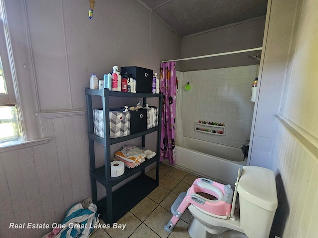 bathroom with wooden walls, tile patterned flooring, shower / bath combo, and toilet