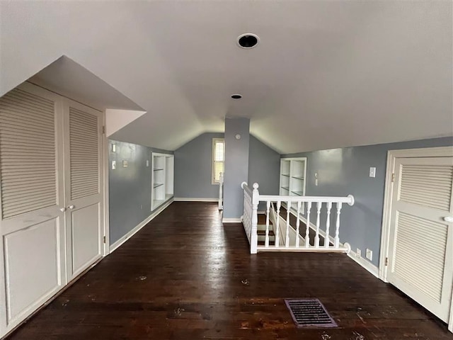 additional living space with lofted ceiling, dark hardwood / wood-style floors, and built in shelves