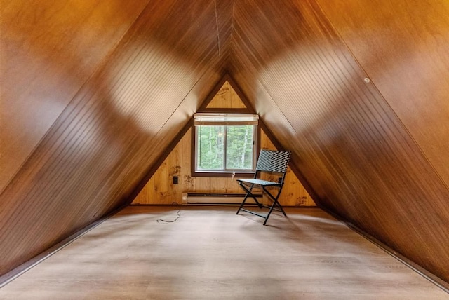 additional living space featuring wood walls, light hardwood / wood-style flooring, lofted ceiling, and a baseboard heating unit