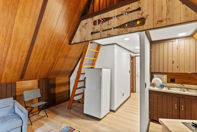 kitchen featuring light wood-type flooring, sink, and wooden walls