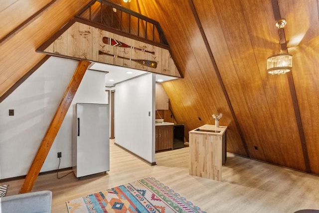 additional living space featuring wooden walls, light hardwood / wood-style flooring, and lofted ceiling