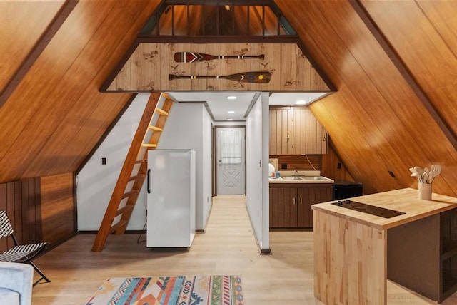 additional living space featuring wood walls, light hardwood / wood-style floors, lofted ceiling, and sink