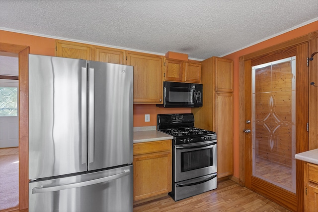 kitchen featuring appliances with stainless steel finishes, a textured ceiling, light hardwood / wood-style floors, and ornamental molding