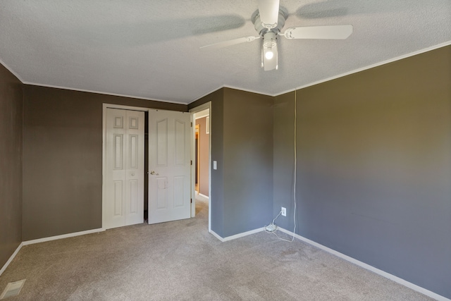 carpeted empty room with a textured ceiling, ceiling fan, and ornamental molding