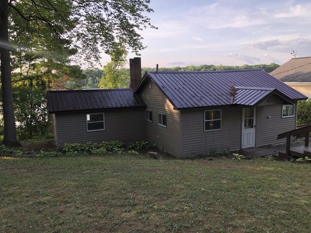 589 E Sidney Rd, Stanton, MI 48888 - back of property featuring a chimney, a lawn, and metal roof
