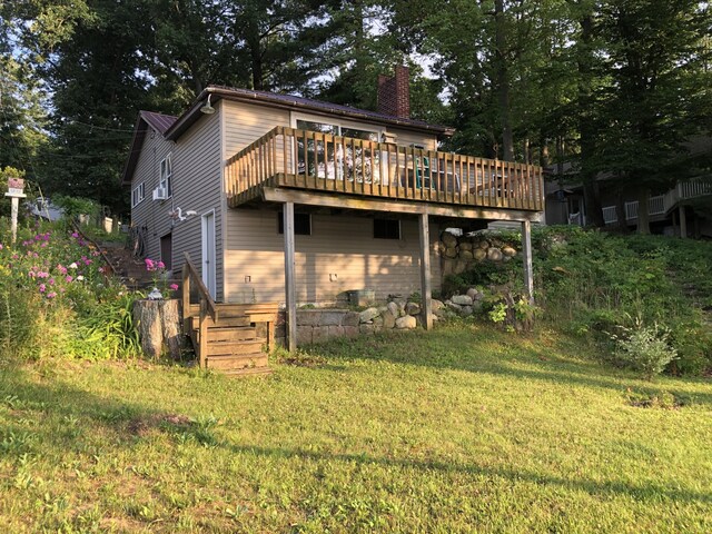 589 E Sidney Rd, Stanton, MI 48888 - back of house featuring a chimney, a wooden deck, and a lawn