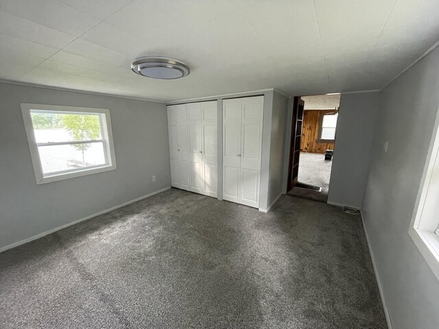 589 E Sidney Rd, Stanton, MI 48888 - unfurnished bedroom with dark carpet, baseboards, and a closet