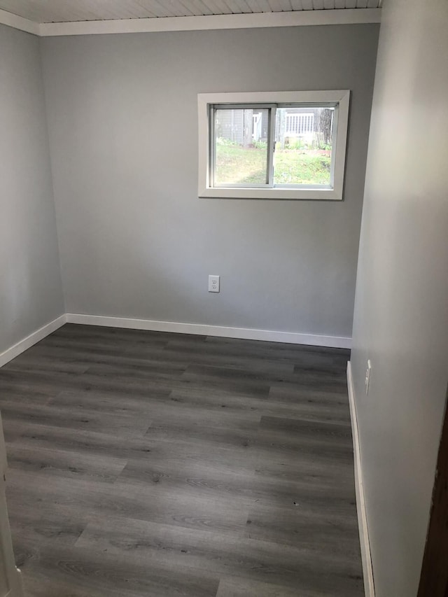 empty room featuring ornamental molding, dark wood-type flooring, and wood ceiling