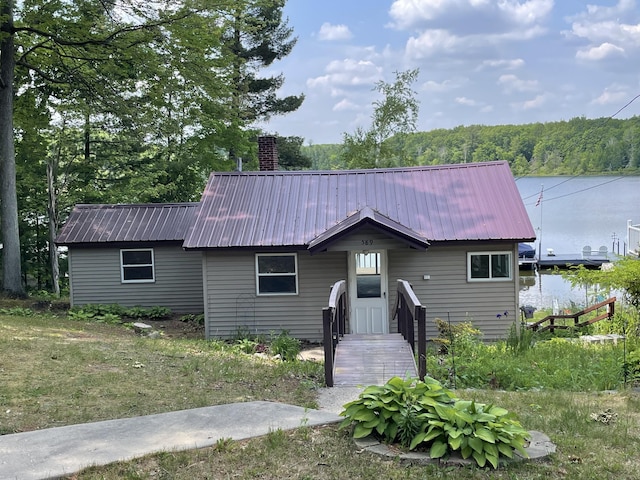 589 E Sidney Rd, Stanton, MI 48888 - view of front of home with a metal roof, a chimney, and a water view