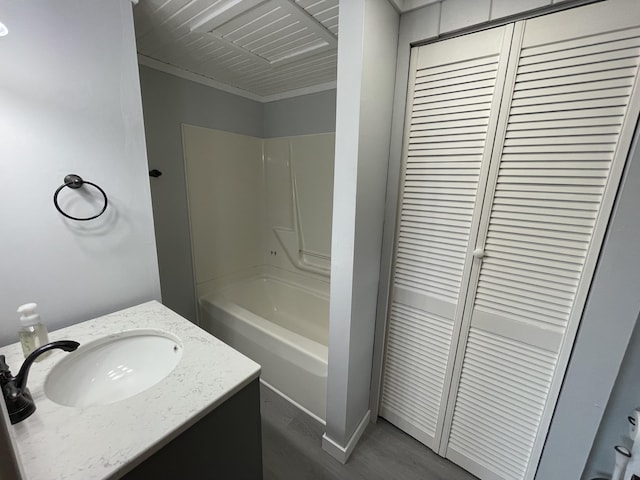 589 E Sidney Rd, Stanton, MI 48888 - bathroom with bathtub / shower combination, vanity, wood finished floors, a closet, and ornamental molding