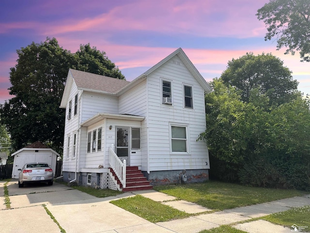 front facade featuring an outbuilding, a yard, and a garage