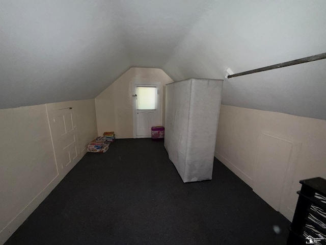 bonus room with dark carpet and lofted ceiling