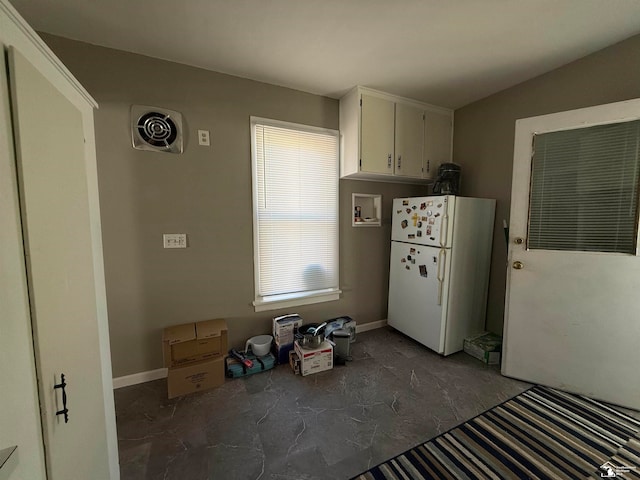 kitchen with white refrigerator, white cabinetry, and lofted ceiling