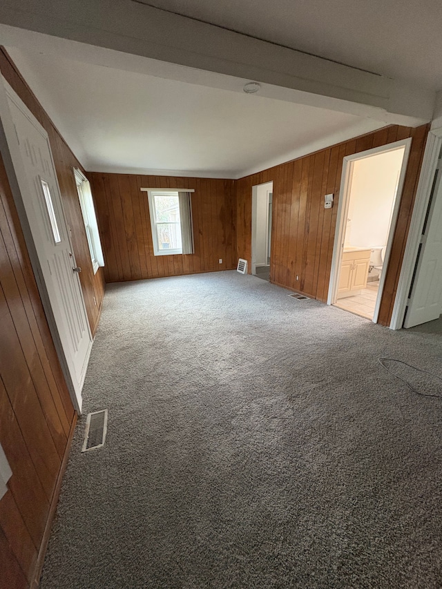 carpeted spare room featuring wood walls