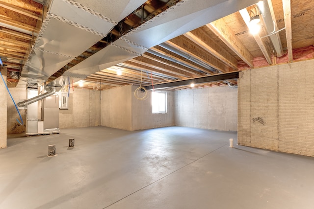 basement featuring electric panel and heating unit