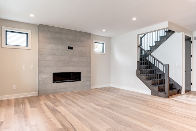 unfurnished living room with a tile fireplace and light hardwood / wood-style floors