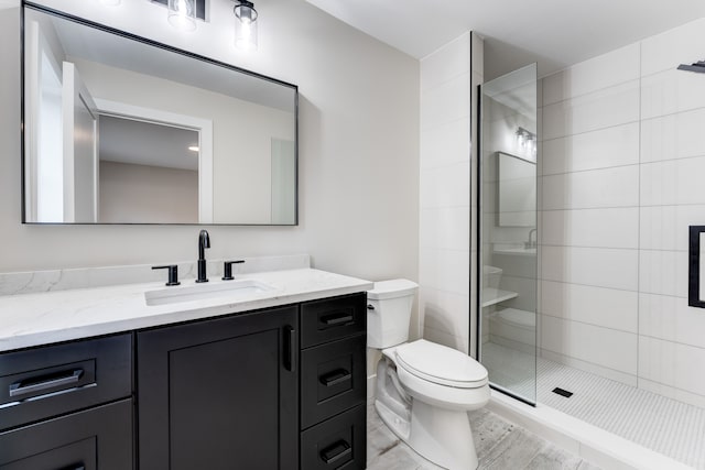 bathroom featuring a tile shower, vanity, and toilet